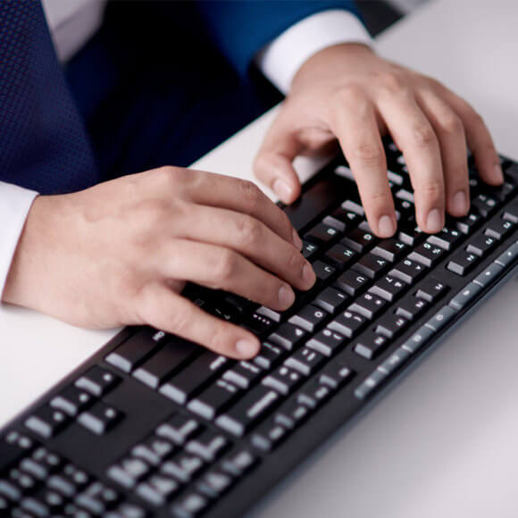 A man typing on a keyboard for web based compliance hotline